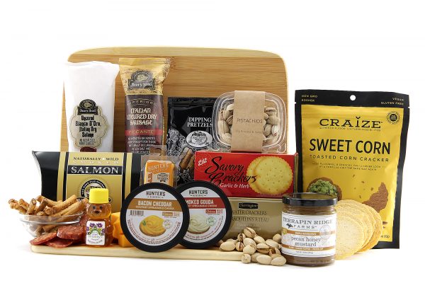 Assorted cheeses, crackers, meats, and more displayed on a bamboo cutting board.