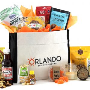 A gift tote filled with made-in-Florida goodies and Florida-inspired flavors. "Orlando The City Beautiful" is printed on the front pocket of the tote bag.